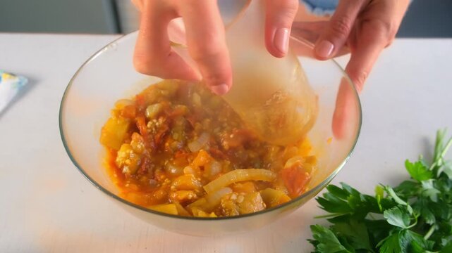 Woman chef hands pressing vegetables stew in bowl using glass cooking on kitchen. Culinary techniques, homemade preparing healthy meal cook food dish, cuisine, seasoning garlic parsley greenery.