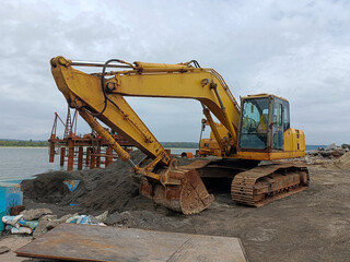 Yellow Hydraulic Excavator Parked at a Coastal Construction Site