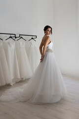 Fashion model in long strapless white dress posing gracefully in studio