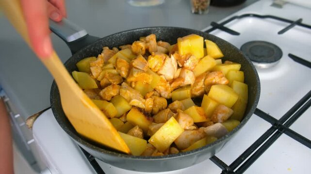 Chef woman hands stirring chicken and potatoes cooking in frying pan on kitchen. Culinary techniques, homemade preparing healthy meal cook meat vegetables food, organic cuisine from fresh ingredients.