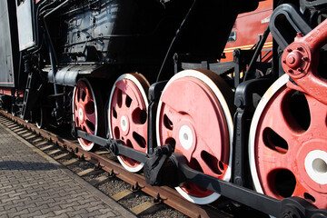 Large metal wheels of a steam locomotive transmitting traction from the locomotive to the rails, industry, close-up