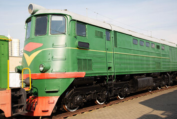 Fototapeta premium Historic green train engine on display at a railway museum showcasing classic transportation history in a city setting