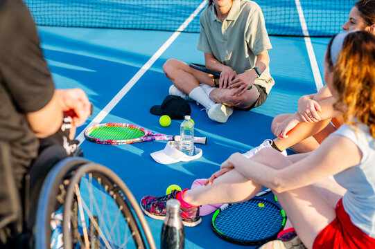 Participants gather on a tennis court, sharing tips and drinks on a sunny afternoon.