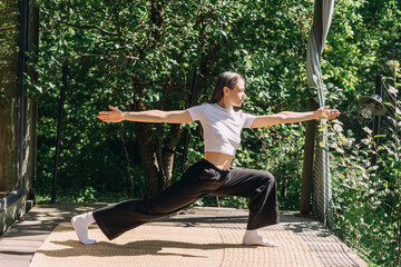 Woman practicing pilates in yoga pants surrounded by greenery in a garden