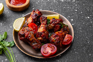 Grilled spicy chicken wings with ketchup on a dark grey background