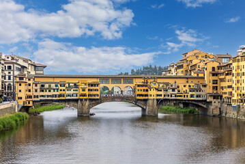 Obraz premium Ponte Vecchio bridge stands over the Arno River in Florence, surrounded by historic buildings.