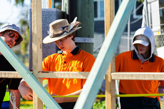 instructor looking on as trainee apprentices measure distance on building frame