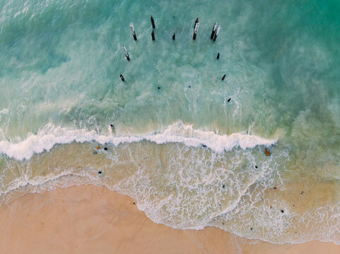 Aerial view of waves washing around derelict wooden pylons at Port Willunga in South Australia