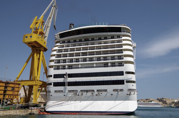Modern cruise ship cruiseship liner being modernized over-hauled repaired refitted maintenanced by shipyard in Malta with dock and cranes