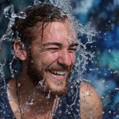 Happy man with water splashing face smiling joyful expression outdoor setting wet hair casual clothing water droplets carefree mood refreshing