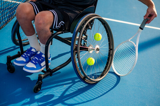 Player with wheelchair engages in tennis practice with bright yellow balls in view
