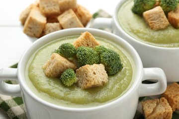 Tasty broccoli cream soup with croutons on table, closeup