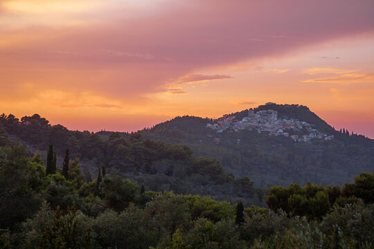 Landscape with a distant greek village on the hill at sunset. Pelekas village, Corfu, Greece