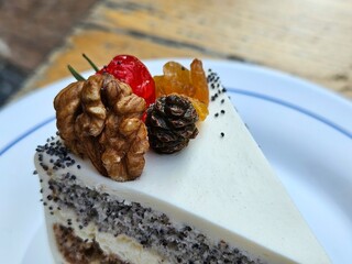 Poppy seed cake with buttercream. Delicious beautiful piece of cake decorated with cream and walnuts on a white plate