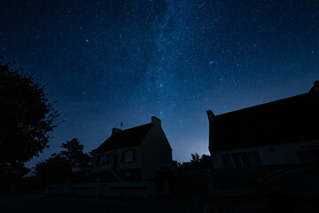 A few house silhouettes against a starry night sky with the Milky Way.
