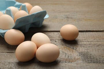 Raw chicken eggs on wooden table, closeup