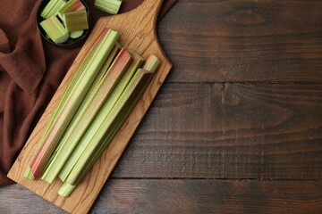 Fresh rhubarb stalks on wooden table, flat lay. Space for text