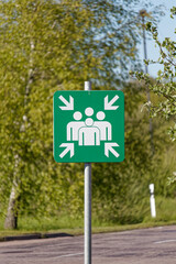 European Green Emergency Muster Point Sign Showing Four People with Arrows