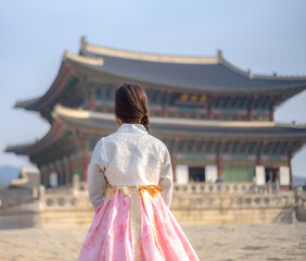 A woman in a vibrant hanbok gazes at the majestic Gyeongbokgung Palace in Seoul, capturing the beauty of Korea’s heritage and timeless tradition