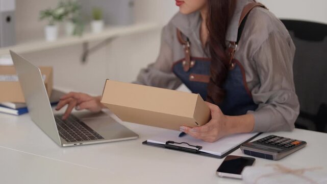 Asian adult woman small business owner home office preparing online orders shipping package ecommerce sales entrepreneur dropshipping logistics management