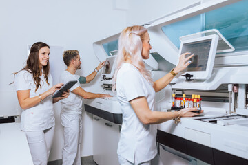 Medical professionals in a lab process samples using advanced equipment while collaborating on tasks and managing data.