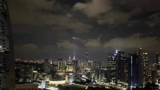 Kuala Lumpur skyline at night featuring illuminated skyscrapers, the iconic Merdeka 118 tower, and vibrant city lights under cloudy skies