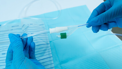 Connecting a urinary catheter to a drainage bag using gloved hands over a sterile medical field.