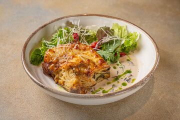 Baked lasagna with salad and creamy sauce