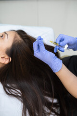 Caucasian female mature patient getting head or scalp injection in cosmetology clinic. Receding hairline, baldness problems, hairloss. Cosmetologist doing injections with syringe. 