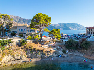 Assos Beach Cove: View of the Small Natural Beach and Pine Trees Against a Mountain and Village Backdrop, Kefalonia