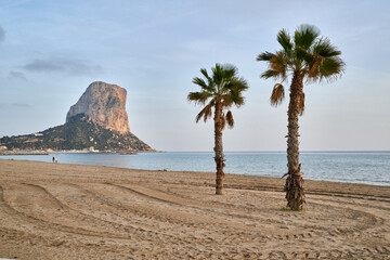 Mediterranean beach coastal landscape Penon de Ifach iconic rock formation Calpe Spain palm tree...