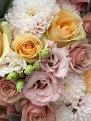 A fresh, delicate bouquet of pink, yellow roses, and white chrysanthemums. The bouquet is in pastel colors. Background