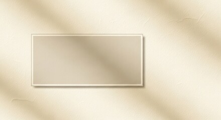A beige rectangular frame on a beige textured wall with a shadow of a tree branch.