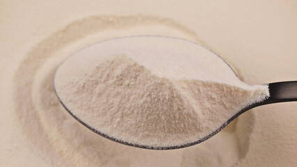 Close-up of a spoon with fine collagen powder on a smooth background. Concept of dietary supplement, protein nutrition and wellness product for health and beauty industries, self care.