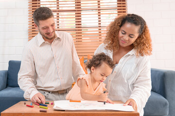 Happy parents playing with their adorable baby at home. Mom and dad looking at their baby who drawing on paper with pencil in cozy living room. Creative education. Early development