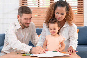 Happy parents playing with their adorable baby at home. Mom and dad looking at their baby who drawing on paper with pencil in cozy living room. Creative education. Early development
