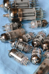 vintage vacuum tubes on blue background, retro electronic components used in radios and amplifiers, close up of glass valves with metal pins