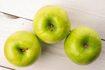 Green juicy apples on a wooden table, macro, top view.