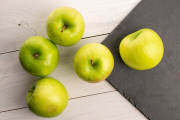 Green juicy apples on a wooden table, macro, top view.