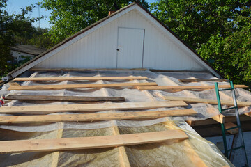 Roofing construction. Repairing the roof frame of the house and covering it with film during the rain.