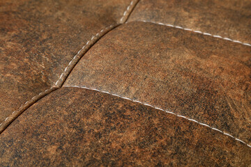 a close up of a beige sofa with tufted upholstery and neatly stitched square patterns.