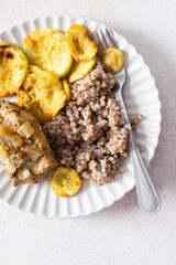 Green buckwheat paired with fried hake, zucchini, and a colorful salad of broccoli, pink radish, and seeds, providing a protein-packed, healthy breakfast to fuel your morning