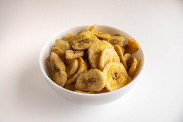 Banana chips in a bowl on a white background. Diet sweets.