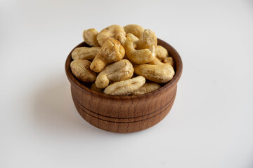 Raw peeled cashew nuts in a wooden bowl.