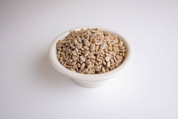 shelled sunflower seeds in a bowl on a white background