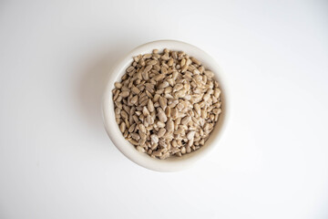 shelled sunflower seeds in a bowl on a white background
