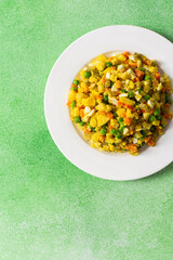 A vibrant salad showcases a mix of boiled egg, tender chicken breast, diced potatoes, sweet carrots, and green peas, all drizzled with olive oil, perfect as a nutritious meal