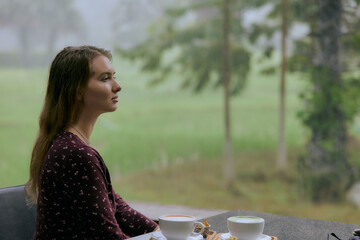 A Serene Moment of Reflection: A Woman Enjoying Her Tea While Gazing Out at a Misty Green Landscape