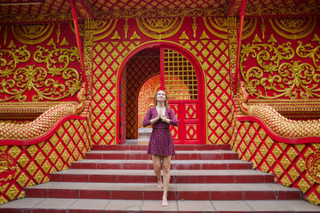 A Woman in a Vibrant Red and Gold Temple Interior with Intricate Designs and Traditional Patterns, Practicing Mindfulness and Serenity in an Enchanting Setting