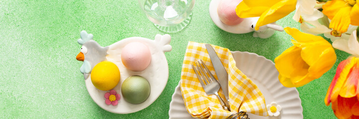A beautifully arranged Easter table setting showcases a decorative egg nestled in a yellow napkin, surrounded by a glass of water and fresh flowers, perfect for holiday gatherings